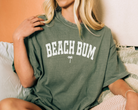 beach shirt that says beach bum with a small palm tree. Color is moss green.