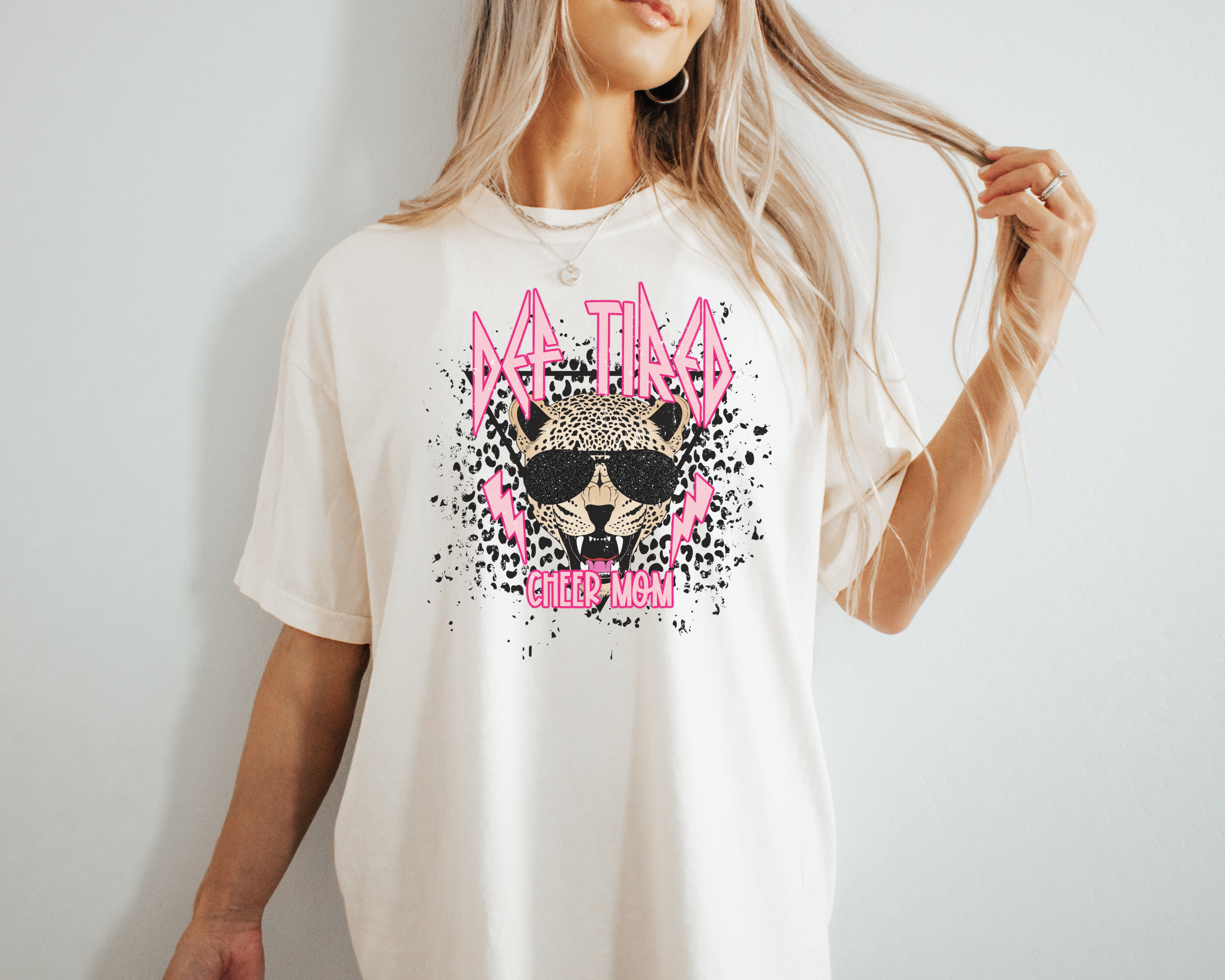 def leopard themed cheer mom tshirt.  The cheer mom graphic tee says def tired cheer mom in pink letting with a leopard head in the middle.