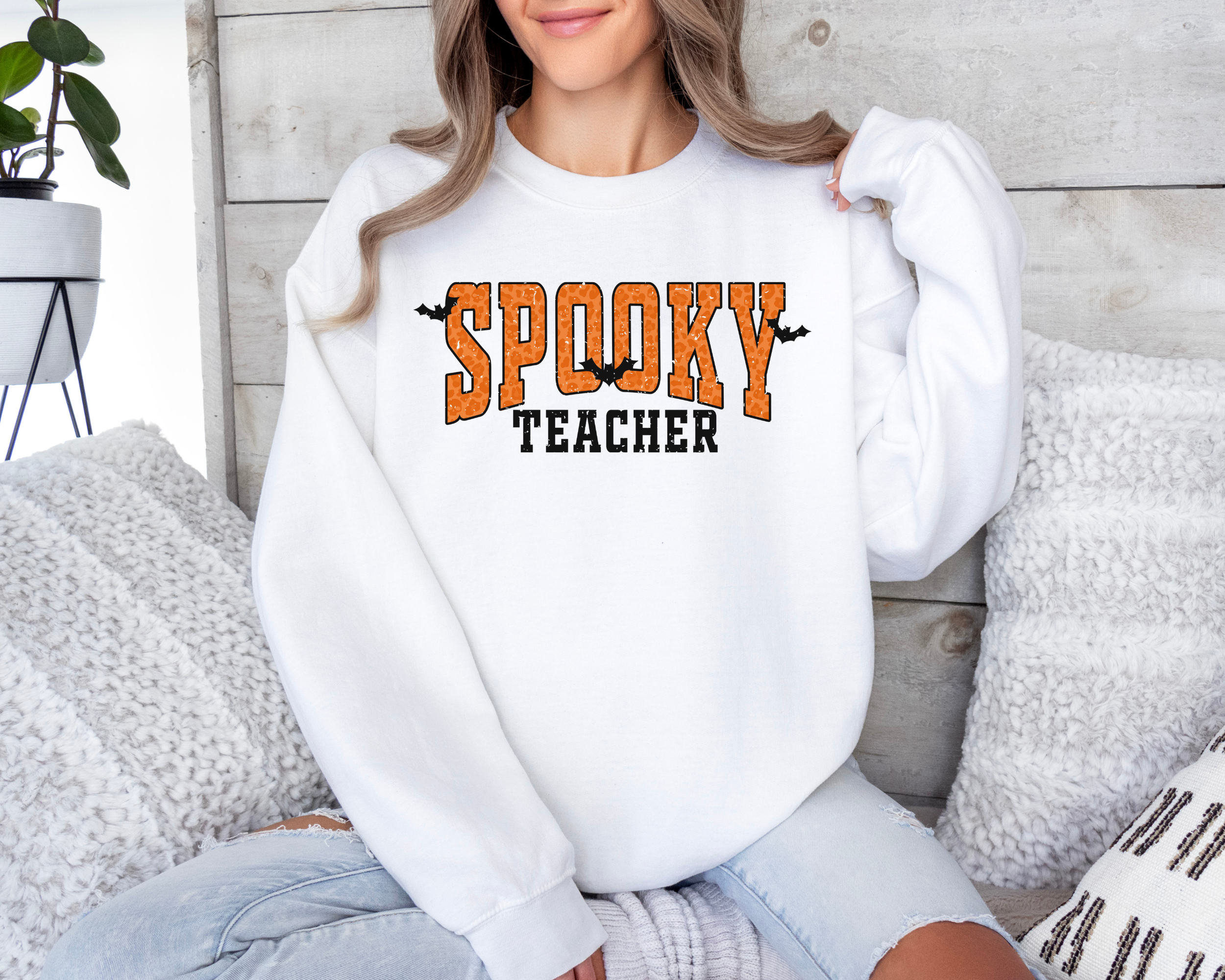 Orange Spooky teacher design on a crewneck sweatshirt in the color white.